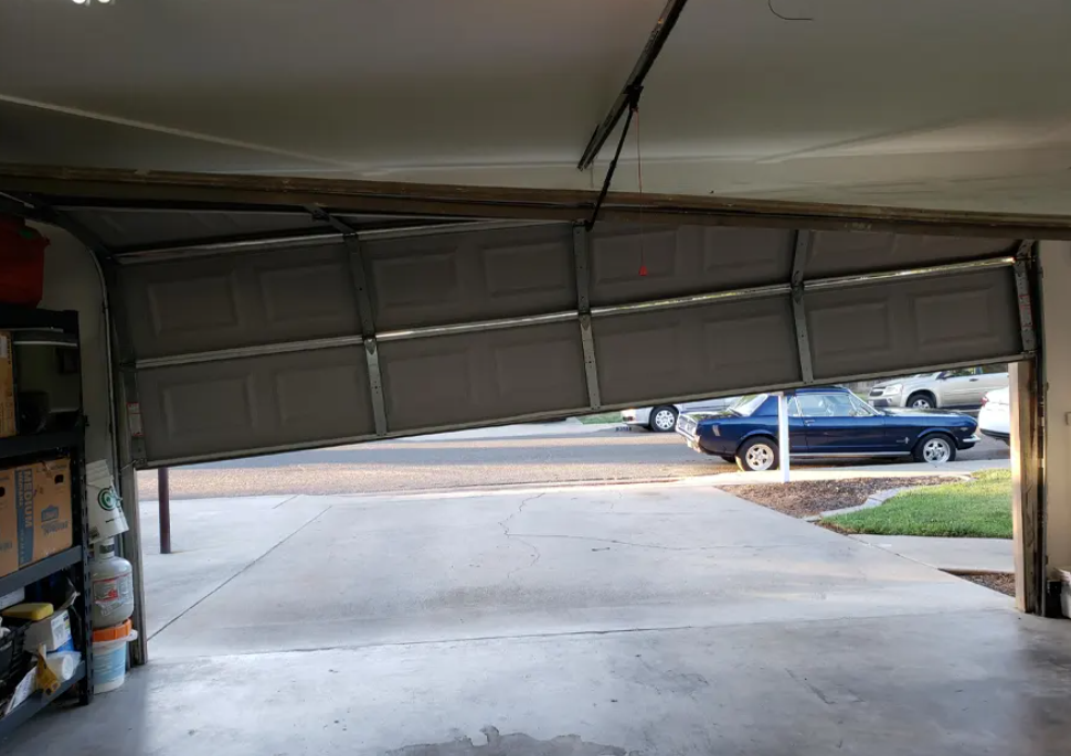 Bent garage door track and loose standard cables causing a dangerous door misalignment