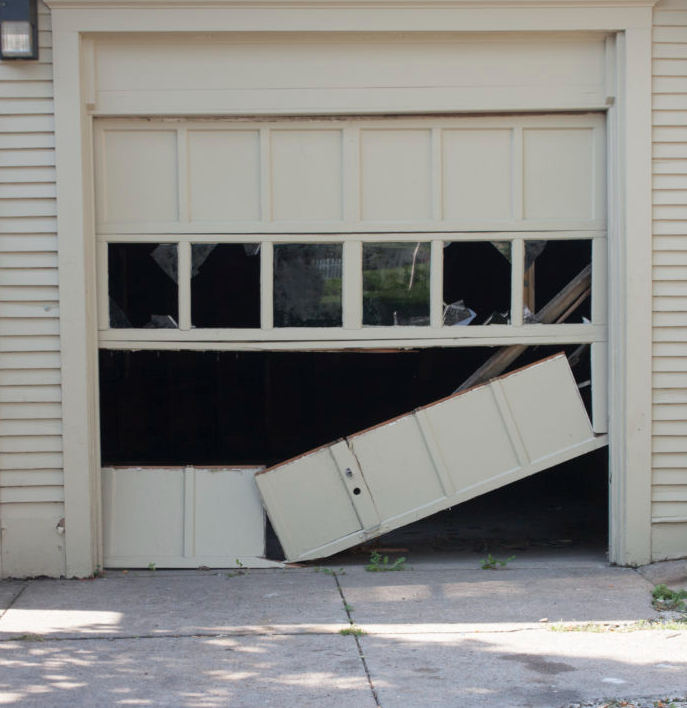 Buckled standard unreinforced garage door sustaining heavy structural damage from coastal winds